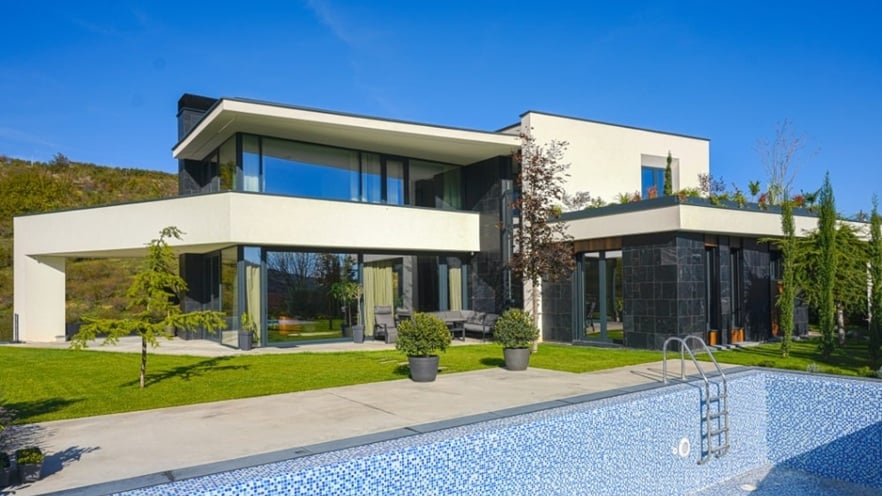 Modern villa with a private pool, large sliding aluminum doors, and a spacious terrace area