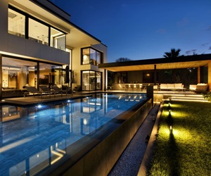 The outdoor area of the house by night: the pool, the garden and the terrace